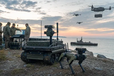 Military team supervising a ground vehicle, quadruped, drones and uncrewed vessel during a coastal exercise