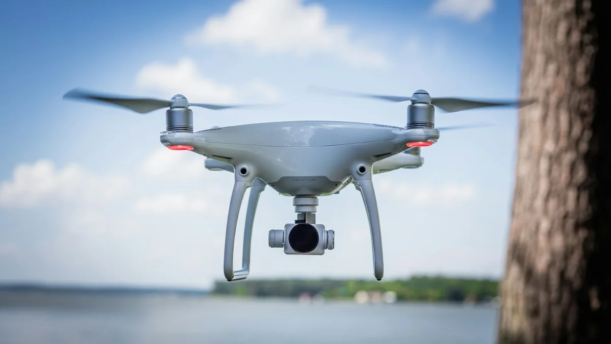 Drone photographié en vol devant un arbre et un ciel bleu